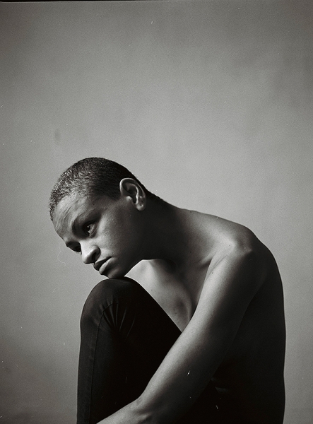 Mirelle Martins, portrait of a bald woman seated in black and white