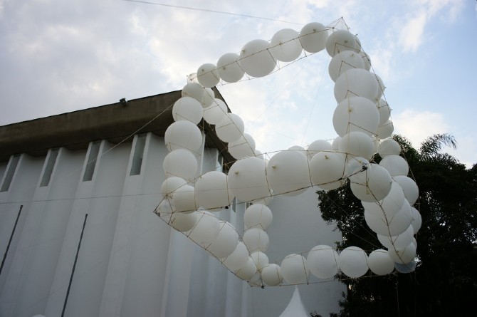 Balloon cube drifting past the dark volume of the museum