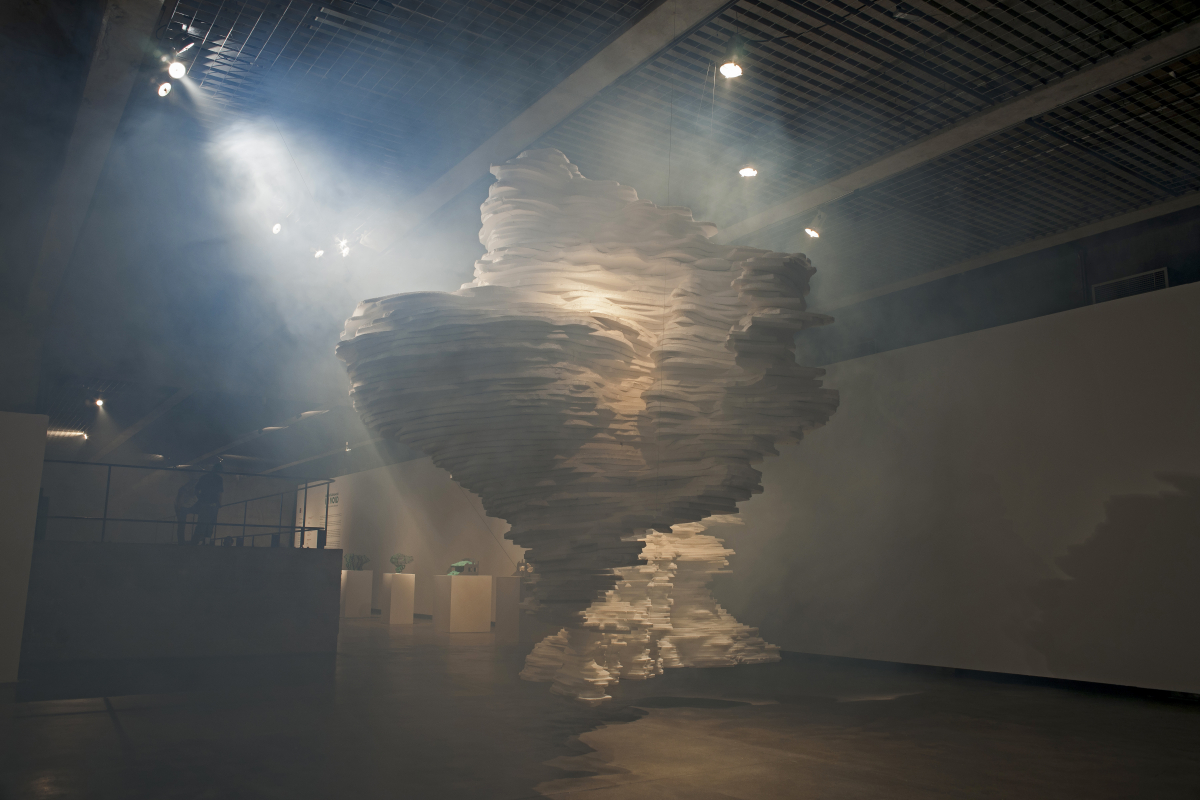 In Void — layered white paper forms spilling across a darkened gallery floor