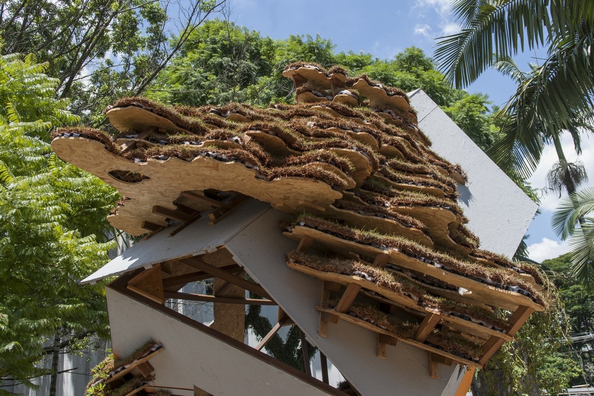 The tilted white cube of Cloudy Thoughts crowned with moss-covered cork forms